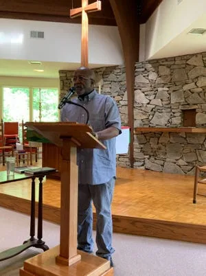 Dwight Mullen, chair of the reparations commission, addresses a crowd at the Episcopal Church of the Holy Spirit in Mars Hill.