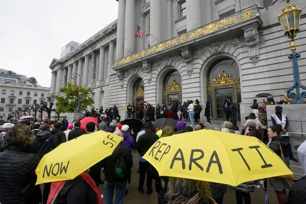 A crowd listens to speakers at a reparations rally outside of City Hall in San Francisco, on March 14, 2023. 