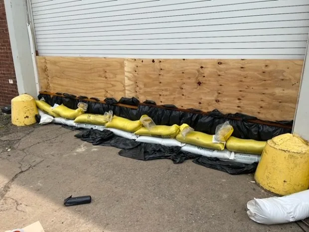 Star Hardware store garage doors being boarded up to prepare for potential flooding on Sunday by owner Max Kothari, his two sons, and his employees.