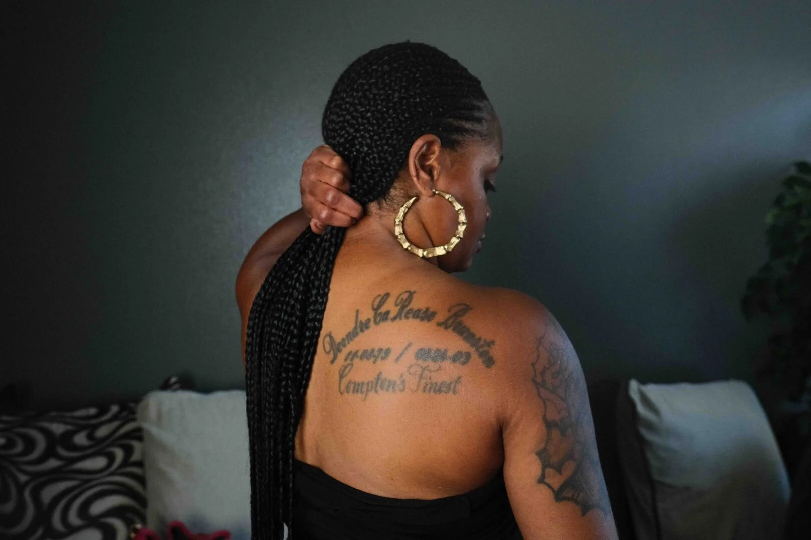 Keishia Brunston, a Black woman, shows a back tattoo commemorating the life of her nephew Deondre Brunston. It shows his name, date of birth and death, and says 