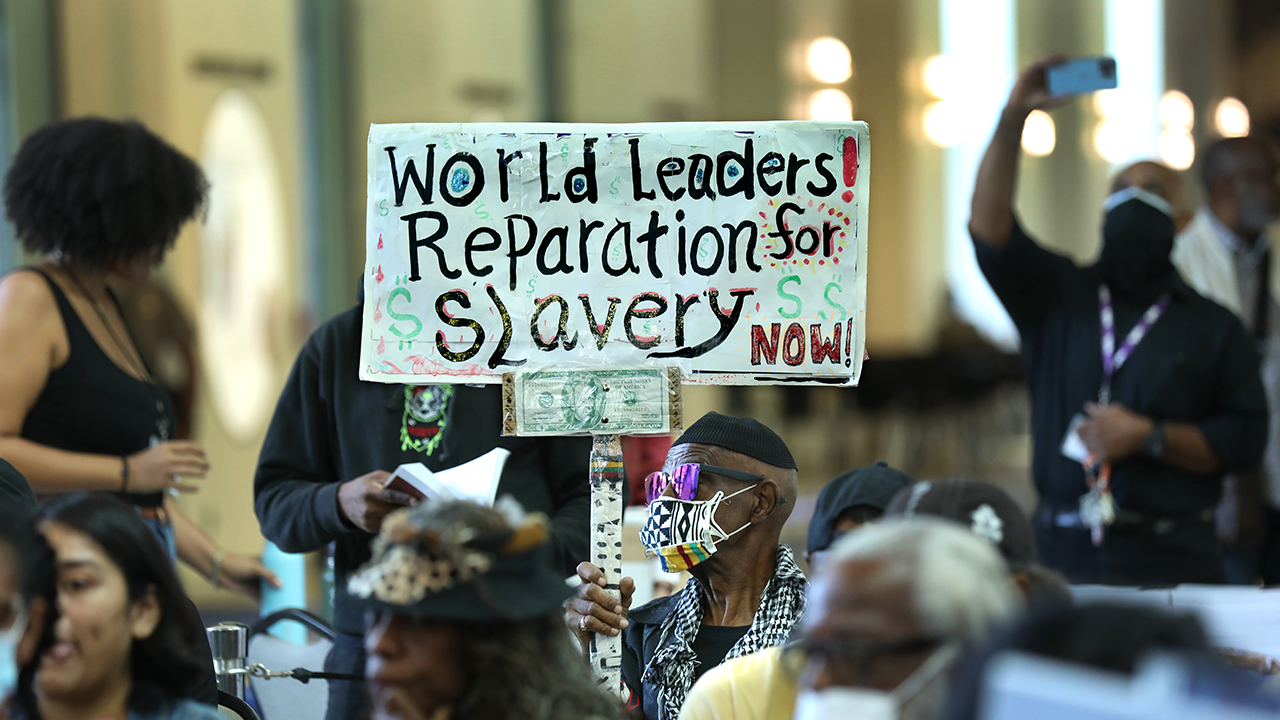 Los Angeles long-time resident, Walter Foster, age 80, holds up a sign as the Reparations Task Force meets to hear public input on reparations at the California Science Center in Los Angeles on Sept. 22, 2022.