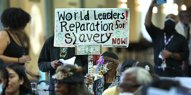 Los Angeles long-time resident, Walter Foster, age 80, holds up a sign as the Reparations Task Force meets to hear public input on reparations at the California Science Center in Los Angeles on Sept. 22, 2022.