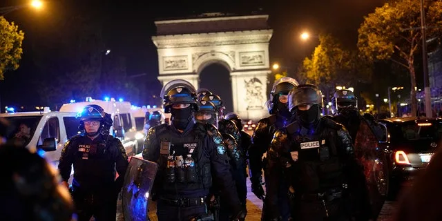 French police in riot gear march near Arc de Triomphe