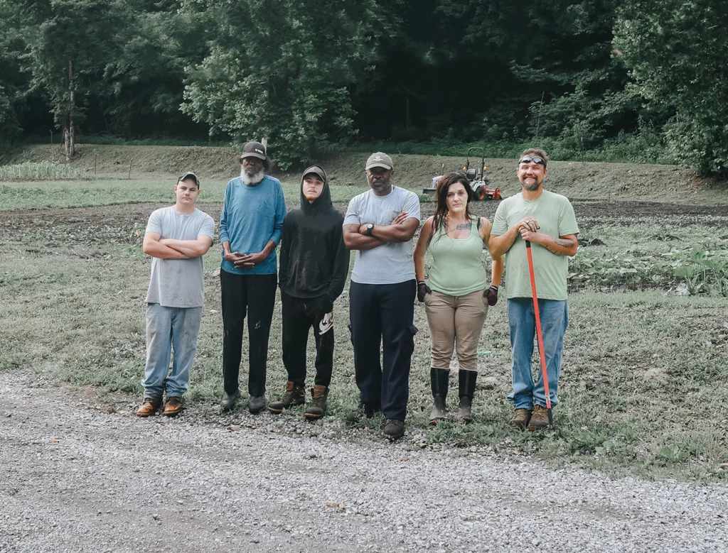 Jason Tartt (center-right in gray shirt) stands with staff and members of the 2023 cohort for his sustainable agribusiness training program through the cooperative McDowell County Farms. From left to right: Tony Mason (crew chief), Donnie Hairston, Johnny Owens, Tartt, Jessica Caskey, Jeffrey Perkins.