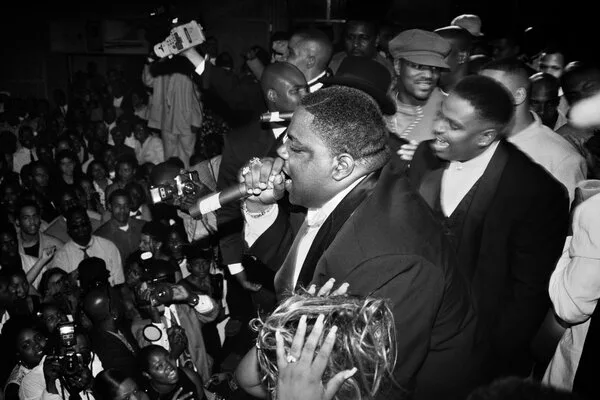 Biggie in a tuxedo with a mic in his hand.