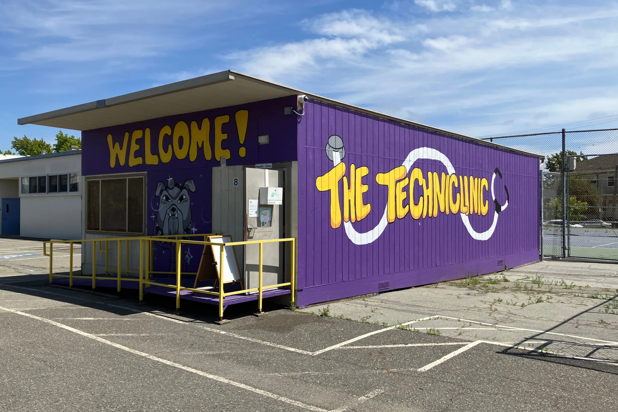 An exterior photo of a clinic painted purple with yellow writing that reads, 