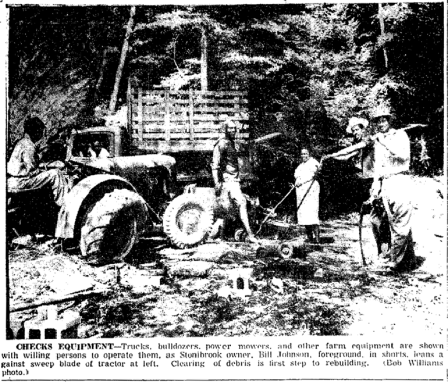 A scan of a news clipping showing Stonibrook owner Bill Johnson and others cleaning up rubble after an arson attack at the Stonibrook property. The photo caption reads: Checks Equipment -- Trucks, bulldozers, power mowers and other farm equipment are shown with willing persons to operate them, as Stonibrook owner Bill Johnson, foreground in shorts, jeans against sweep blade of tractor at left. Clearing of debris is first step to rebuilding.