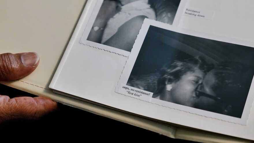 A black-and-white photograph of two people kissing is displayed in a scrap book.