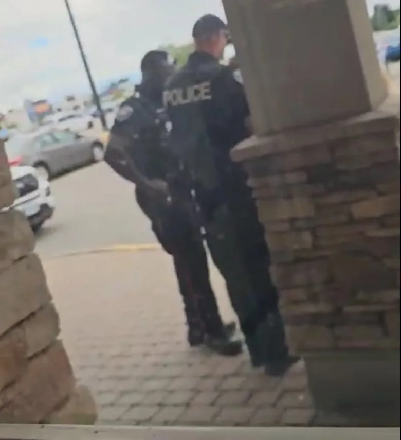 The back and side of two police officers outside a bank.