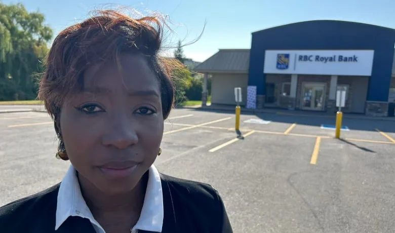 A woman poses for a photo outside a bank branch in early autumn.