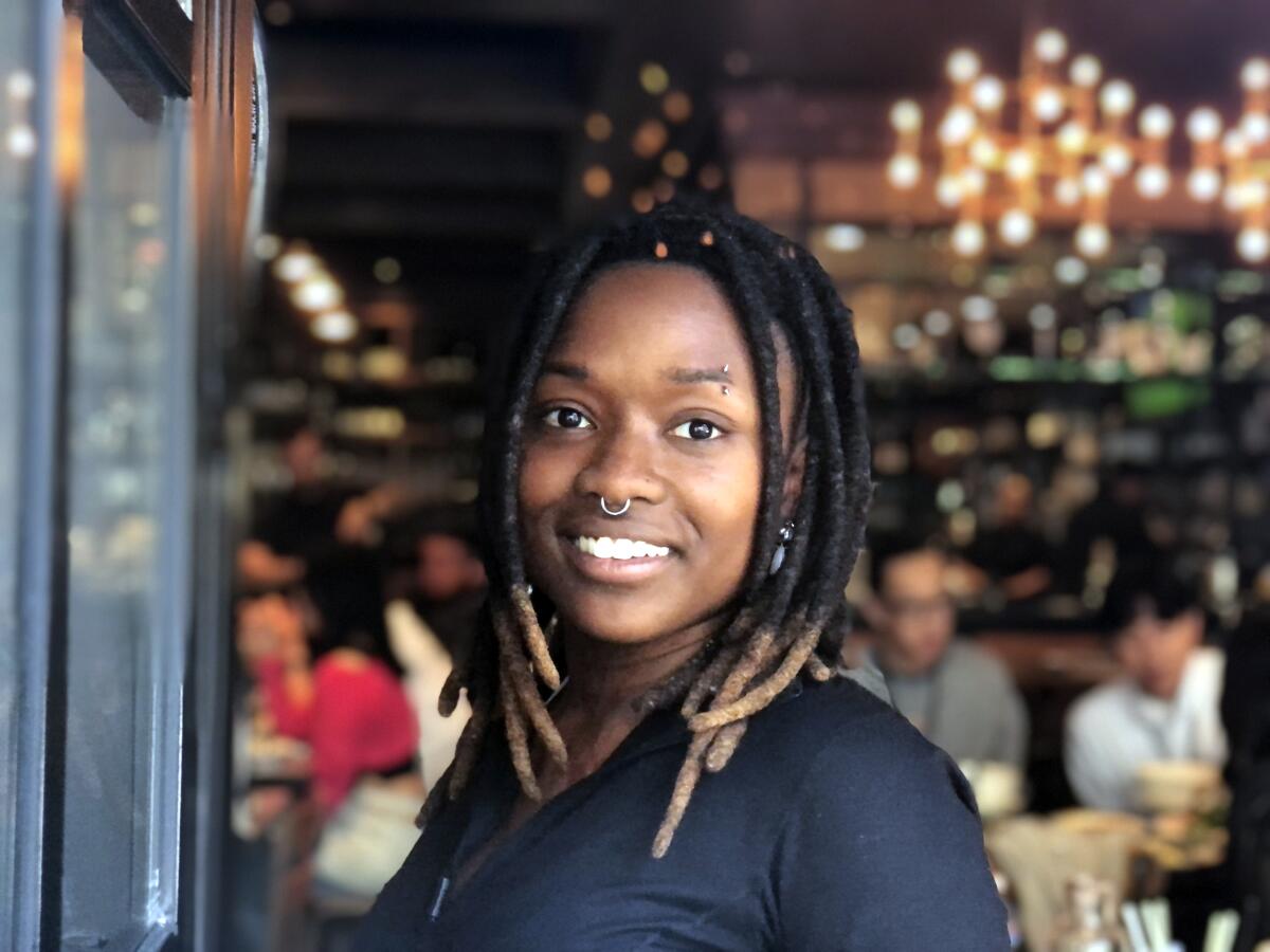 Alyssia Aliyy, 24, a server at Little Sister restaurant in downtown Los Angeles, poses in the window of her workplace.