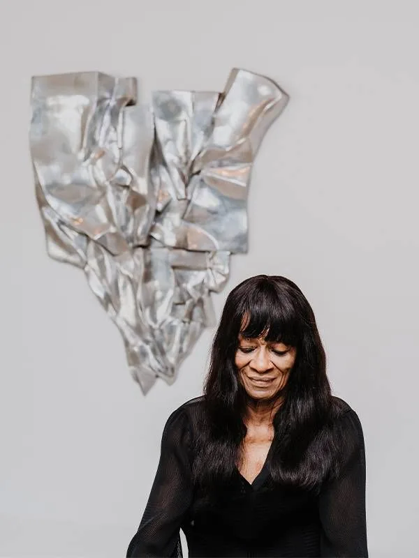 Portrait of a woman in front of a silver sculpture. Next Avenue, Barbara Chase-Riboud