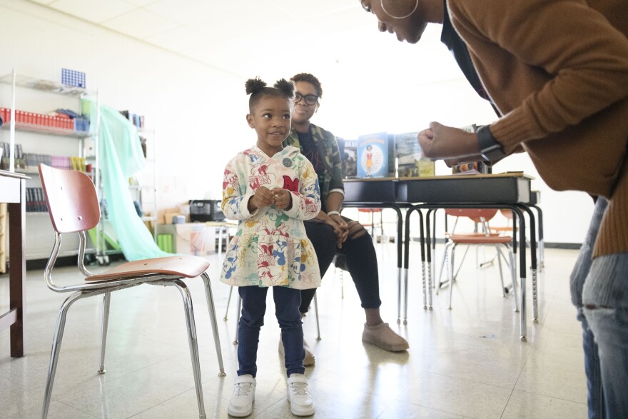 Teacher Areyell Scott discusses the story of Ruby Bridges with kindergartener Caiya Nemons as a second teacher, Cameil Jones Barrett, looks on. The women said that when teaching young children about racism, it's important to balance the uncomfortable truth by imparting a sense of empowerment.