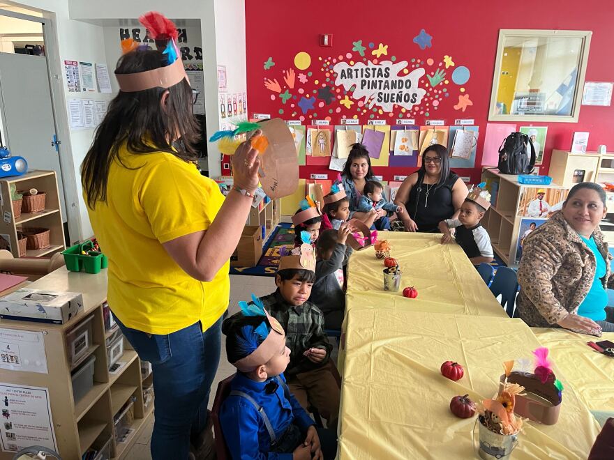 Giovanna Fraioli waves a turkey party-style hat in the air to a group of parents and kids as part of the holiday celebrations.