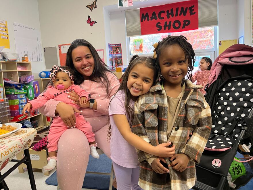 Shane Gonzalez sits with her 9-month-old baby on her lap while her 5-year-old daughter hugs another student.