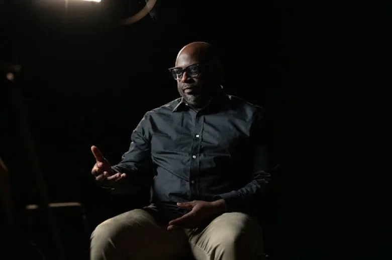 David Austin is seated in a chair while being interviewed.