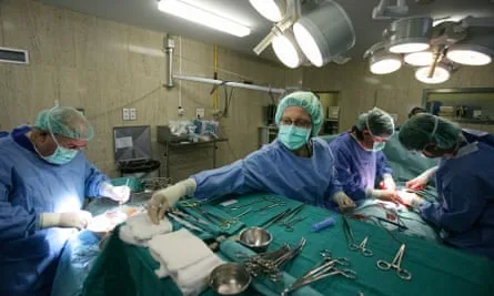 Doctors performing organ transplant surgery in hospital operating room.