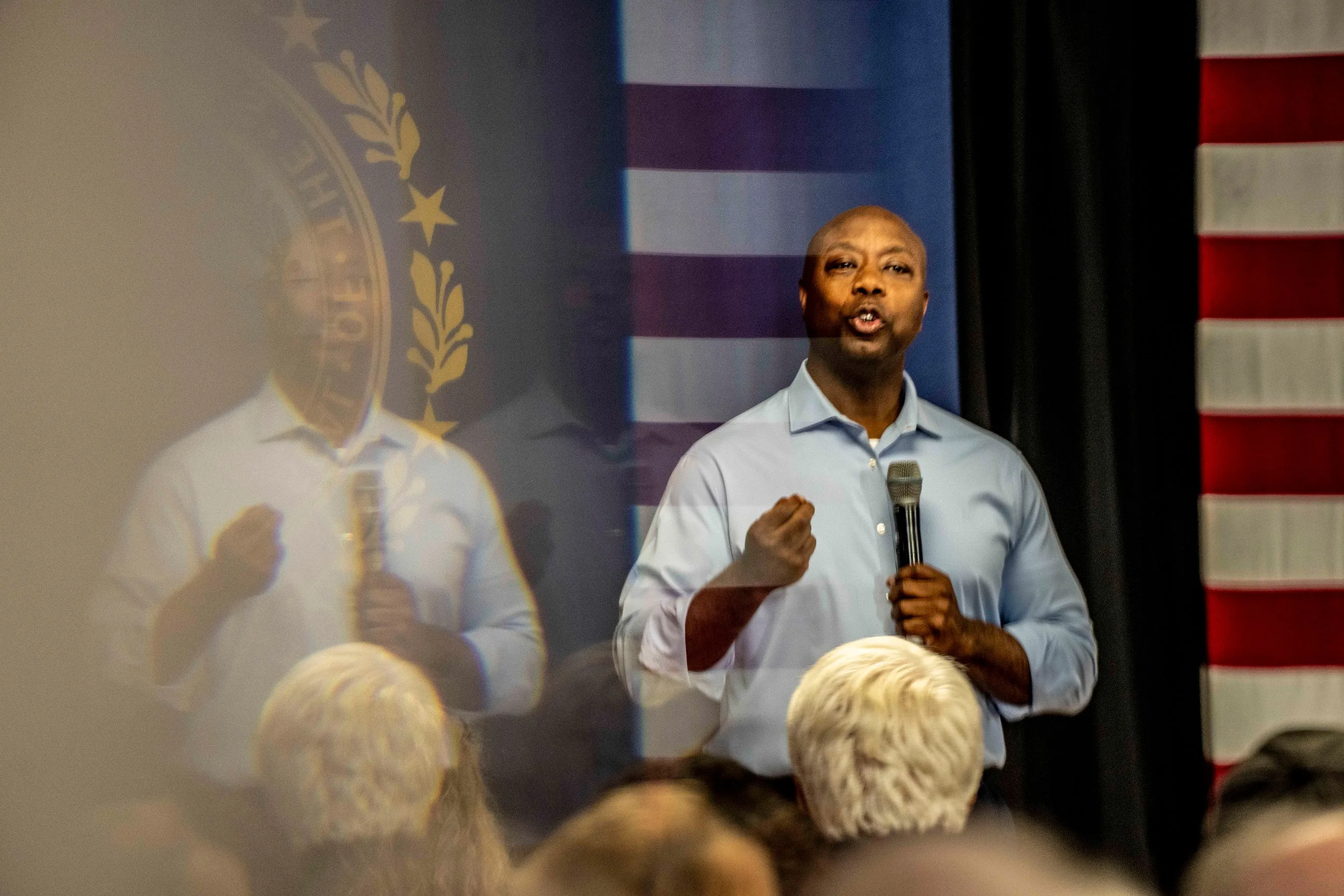 Senator Tim Scott speaking at a town hall in New Hampshire wearing a light blue buttonup shirt and holding a microphone...