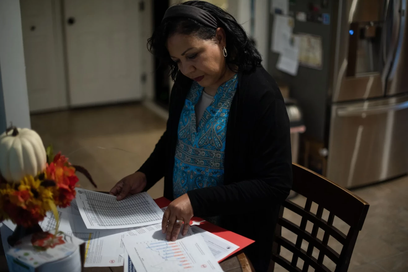 Cassandra Carter opens a packet of materials explaining the dangers of fentanyl use and drug abuse statistics at her kitchen table on Oct. 31, 2023.