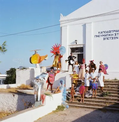 A group of people standing on steps before a building with Greek lettering on its facade.