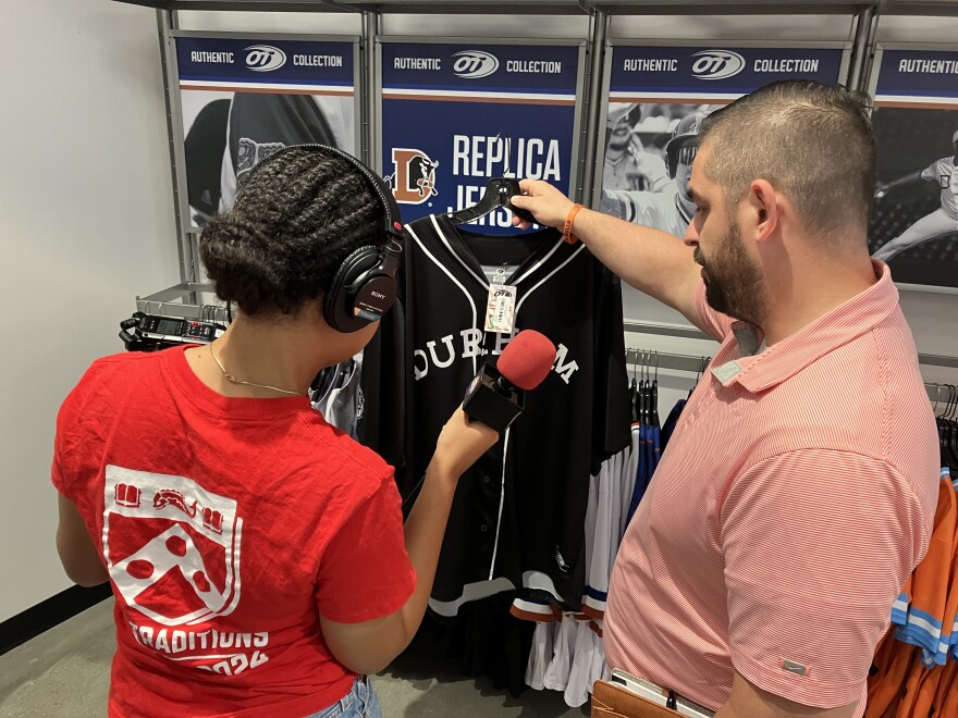  Bulls General Manager Tyler Parsons shows Youth Reporter Olivia Haynie the Durham Black Sox replica jersey.