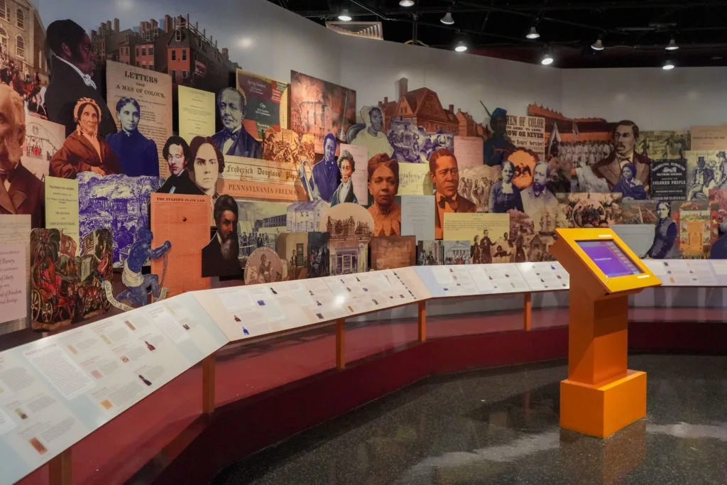 Portraits decorate a wall inside of a museum with a podium in front of it