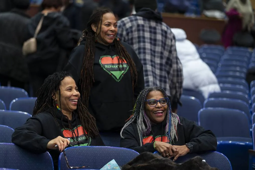 Melody Marion Bickhem, center from Wheeling, checks the selection order during the City of Evanston Reparations Committee meeting with her sisters Marvella Bowen, left and Adriene Strickland, right, at Evanston Township High School on Thursday, January 11, 2024 in Evanston, Illinois. About 200 people attended the meeting to find the selection order of direct descendants who will receive reparations funding.  ( John Konstantaras-Pioneer-Press ) 3155975_ct-evr-reparations-event