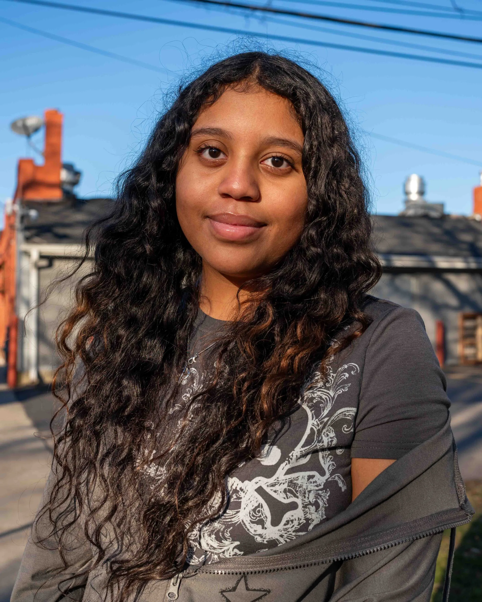 Brown & Black girls support Working on Womanhood: portrait of young woman with long, dark hair, standing outside.