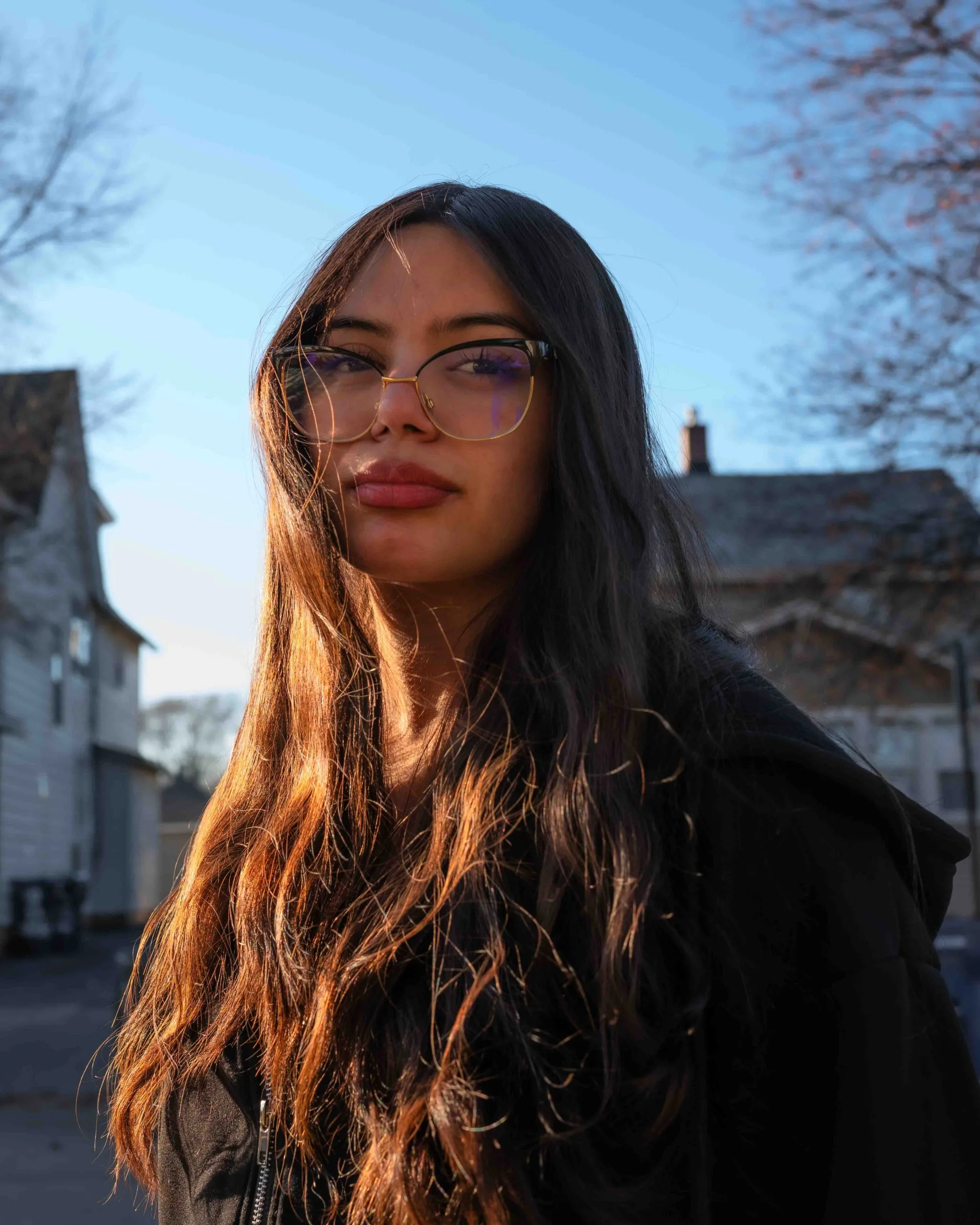 Brown & Black girls support Working on Womanhood: portrait of young woman with long, dark hair, standing outside.