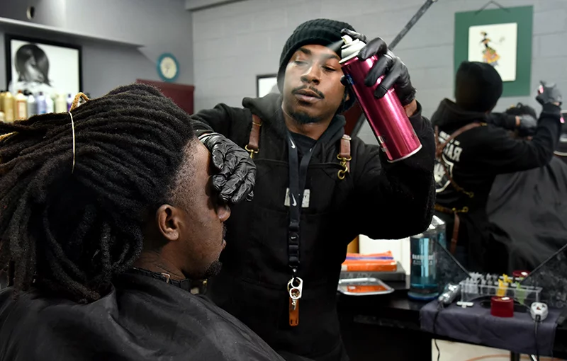 Camren Thurman gives his cousin, Joseph Mosley, a fade and maintenance touch up. A barber for several years, Camren has had a chair for two years at Winning Coiffures, one of 26 locations that are supporting better mental health in Black communities.