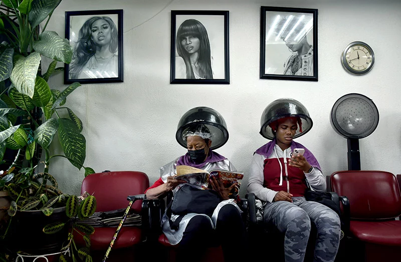 Longtime clients Brenda (left) and Daja Thomas relax under the hair dryers at Winning Coiffures on Colfax Avenue in Denver. Salon owner Rosalyn Redwine dyed Daja’s hair red and orange. “She makes you feel welcome,” Daja said. Photo by Sonya Doctorian.