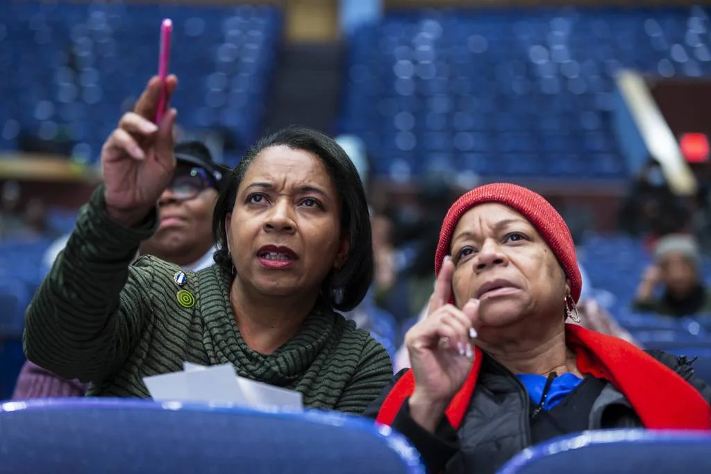 Vanessa Johnson-McCoy, left, and her sister Loretta Johnson look for their unique identification number for reparations during the Evanston reparations committee meeting at Evanston Township High School on Thursday, January 11, 2024 in Evanston, Illinois. About 200 people attended the meeting to see the random selection order of direct descendants who will receive $25,000 each in reparations funding. On the list of 454 direct descendants, Vanessa Johnson was number 58 and Loretta Johnson was number 78 for distribution of the funding. The city has enough funding to support payments for the first 80 descendants in the sequence and hope to begin disbursing payments in March.  ( John Konstantaras-Pioneer-Press ) 3155975_ct-evr-reparations-event