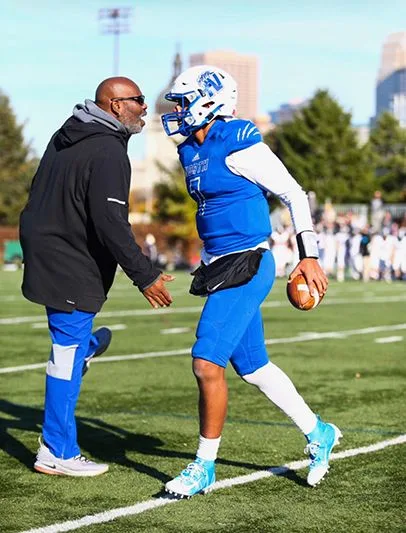 Corey Yeager talking to a football player on the field