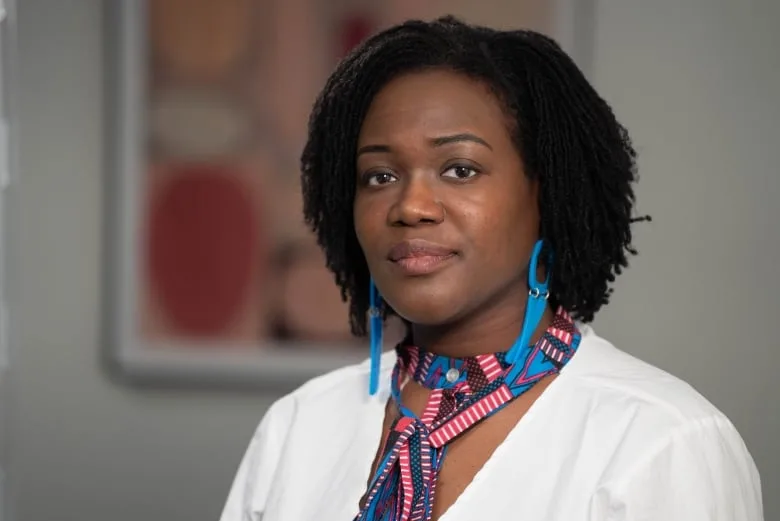 A female family physician wearing a striped tie and blue earrings. 