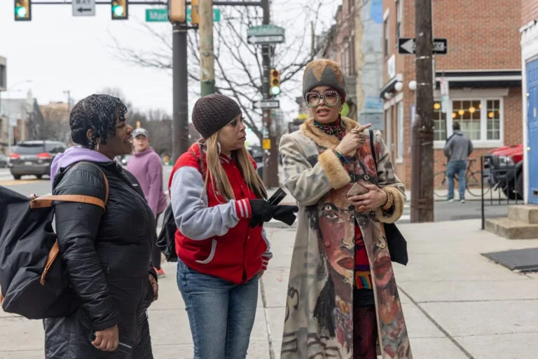 The Sisterhood Sit-In Trolley Tour’s guide, Starfire (right) talks with members of Philadelphia’s 40+ double dutch team outside Harriet’s Bookshop on March 9, 2024