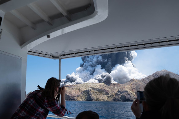 Tourists on a boat look at the eruption of the volcano on White Island, New Zealand, on December 9, 2019. 
