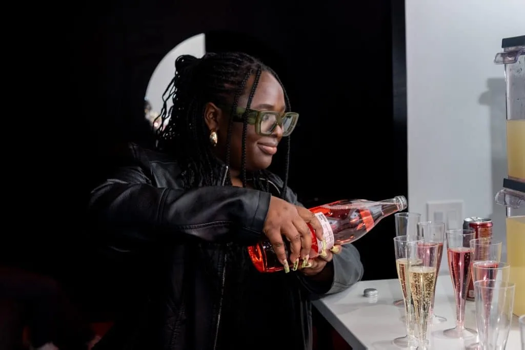 Black woman pours red cider in glass