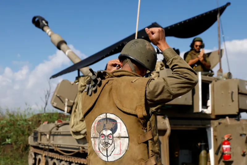 An Israeli soldier wearing a patch on the back of his flack jacket showing Lebanon's Hezbollah leader Hassan Nasrallah as a target, stands in front of a self-propelled artillery howitzer in Upper Galilee in northern Israel, as an artillery unit shells southern Lebanon on January 4, 2024.