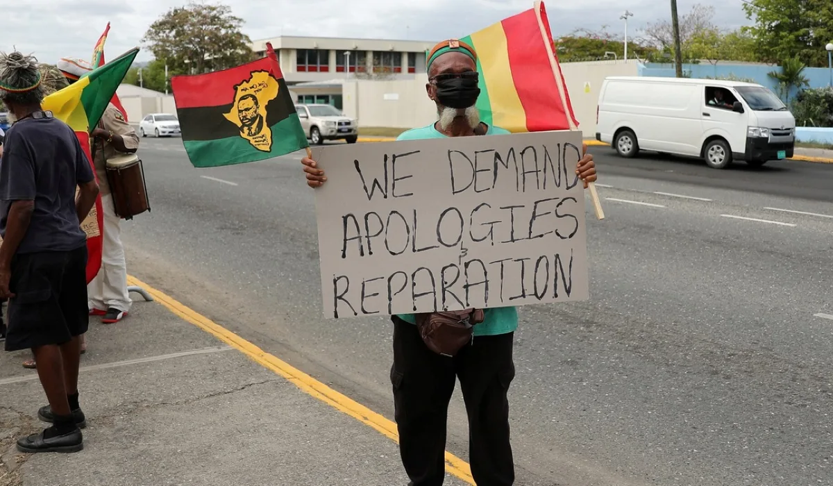 A protester holds a sign during a rally to demand that the United Kingdom make reparations for slavery, ahead of a visit to Jamaica by the Duke and Duchess of Cambridge as part of their tour of the Caribbean, outside the British High Commission in Kingston, Jamaica on March 22, 2022. PHOTO | REUTERS