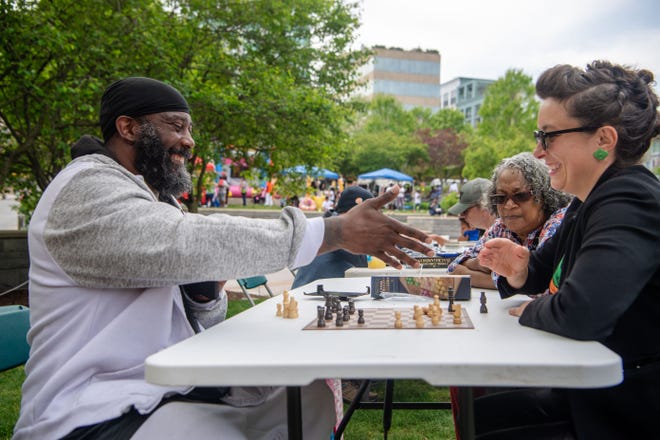 Knowledge Green, left, reaches to shake hands with Asheville City Council member Kim Roney after winning their game of chess at the Community Reparations Jamboree at Pack Square Park in Asheville, April 27, 2024.