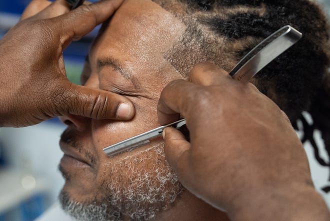 J. Divine Alexander cuts LaRon Williams' hair on Sunday, June 23, 2024, at his barbershop in Louisville, Ky. Alexander, 50, is a participant in The Confess Project, a national mental health effort that trains barbers and stylists to be mental health advocates in Black communities, in which a longstanding stigma often surrounds mental health care. Such programs tap into the open conversation spaces that barbershops and salons create to address underlying issues and connect customers with resources when necessary.