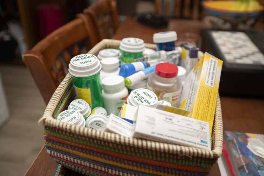 A basket of pill bottles and boxes sit on the dinning room table of Bonnie Steele's home.