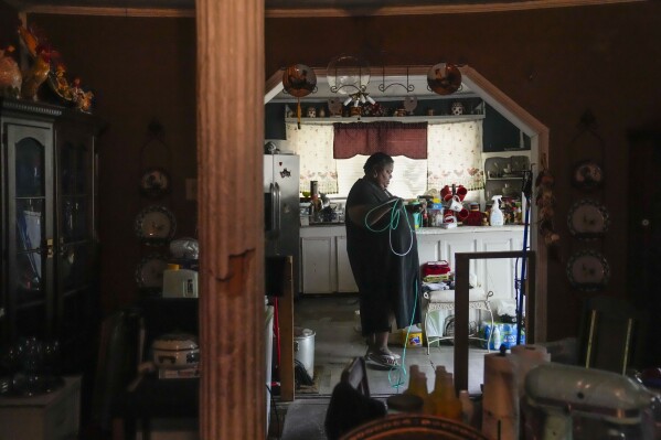 Shelia Mae Dobbins walks with her oxygen tube inside her home in Gloster, Miss., Wednesday, May 29, 2024. Dobbins feels her life — and health — were better before Drax began compressing tons of wood chips nearby, (AP Photo/Gerald Herbert)