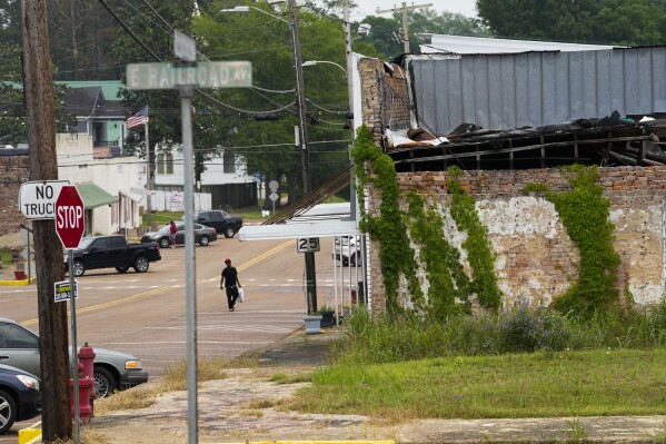 A man crosses the street in downtown Gloster, Miss., Thursday, May 2, 2024. (AP Photo/Gerald Herbert)