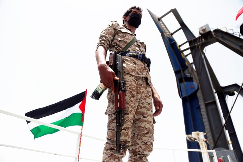 A Houthi fighter guards the Galaxy Leader vessel on the Red Sea coast off Hudaydah, Yemen.