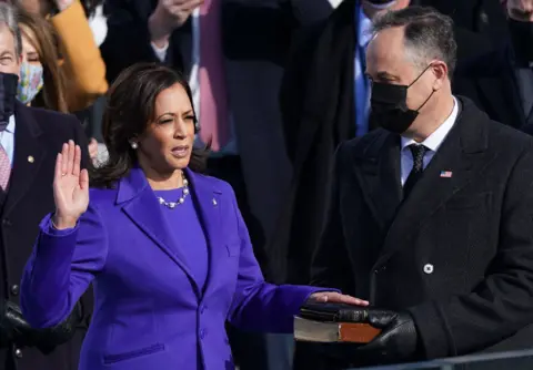 Reuters Kamala Harris wears a purple suit and places her hand on a book as she takes the oath of office