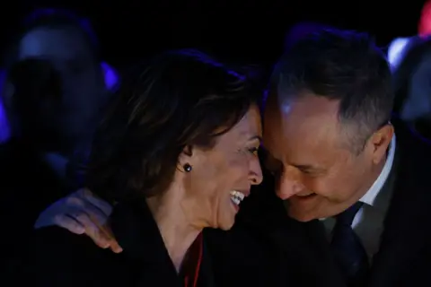 Bloomberg via Getty Images Kamala Harris leans into her husband Doug Emhoff and smiles