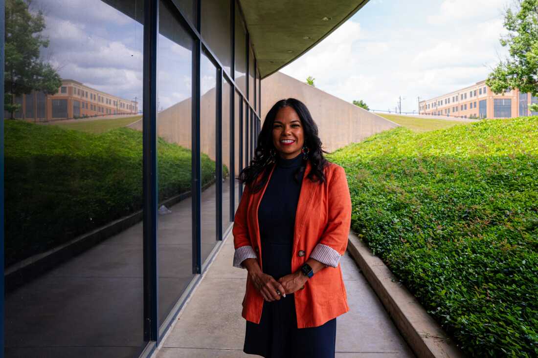 In this photo, Natalie Hernandez-Green, an associate professor of obstetrics and gynecology and the executive director of the Center for Maternal Health Equity at Morehouse School of Medicine, stands on a walkway while wearing a black dress and orange blazer.