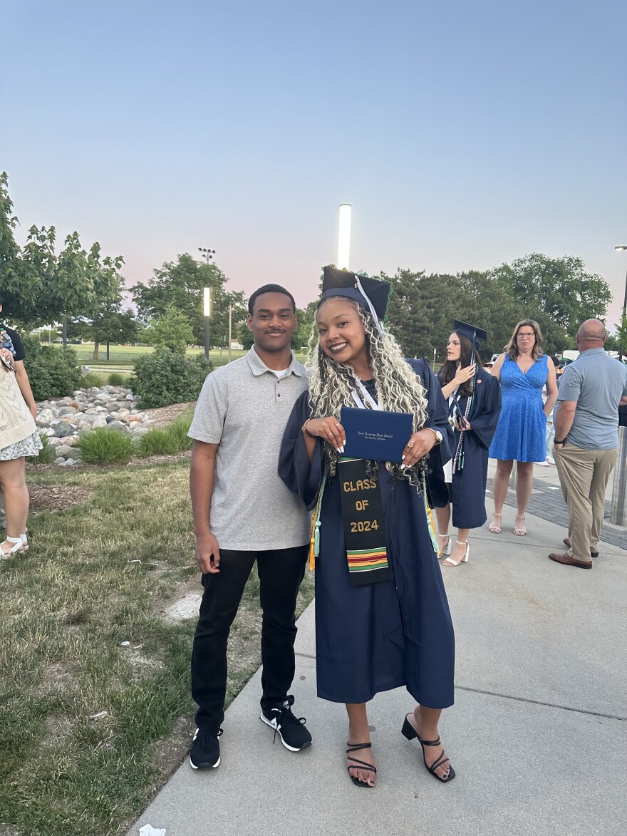 Olivia Burns posing with a loved one in her cap and gown at East Lansing High School's graduation