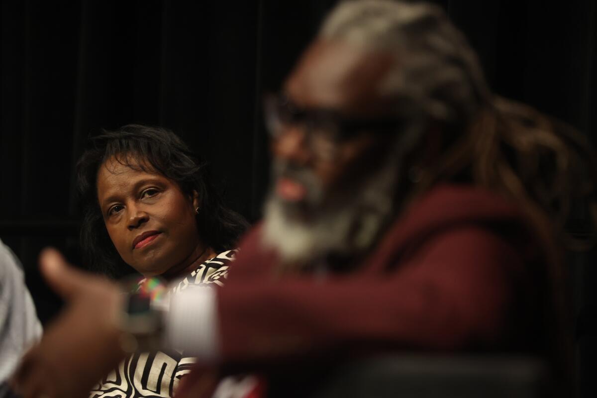 A woman, in focus, listens as a man, out of focus in foreground, speaks 